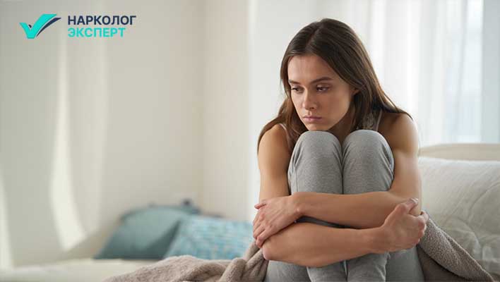 Девушка в депрессии сидит на кровати